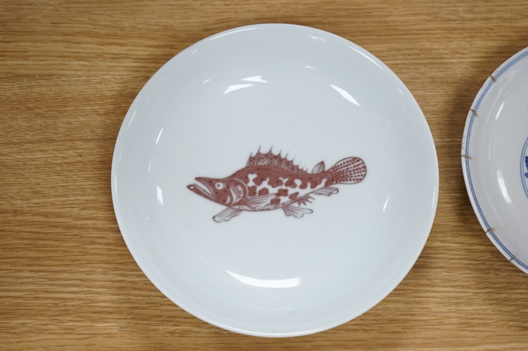 A Chinese underglaze copper red ‘fish’ dish and a blue and white dish, Zhengde mark but later, largest 22cm